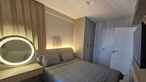 Un dormitorio con una cama, un espejo de tocador, un armario y una lámpara de pared.