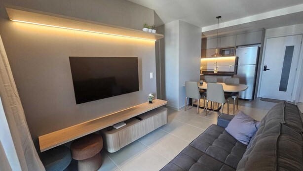 Una sala moderna con un televisor de pantalla plana, un sofá y un comedor con sillas y una mesa.