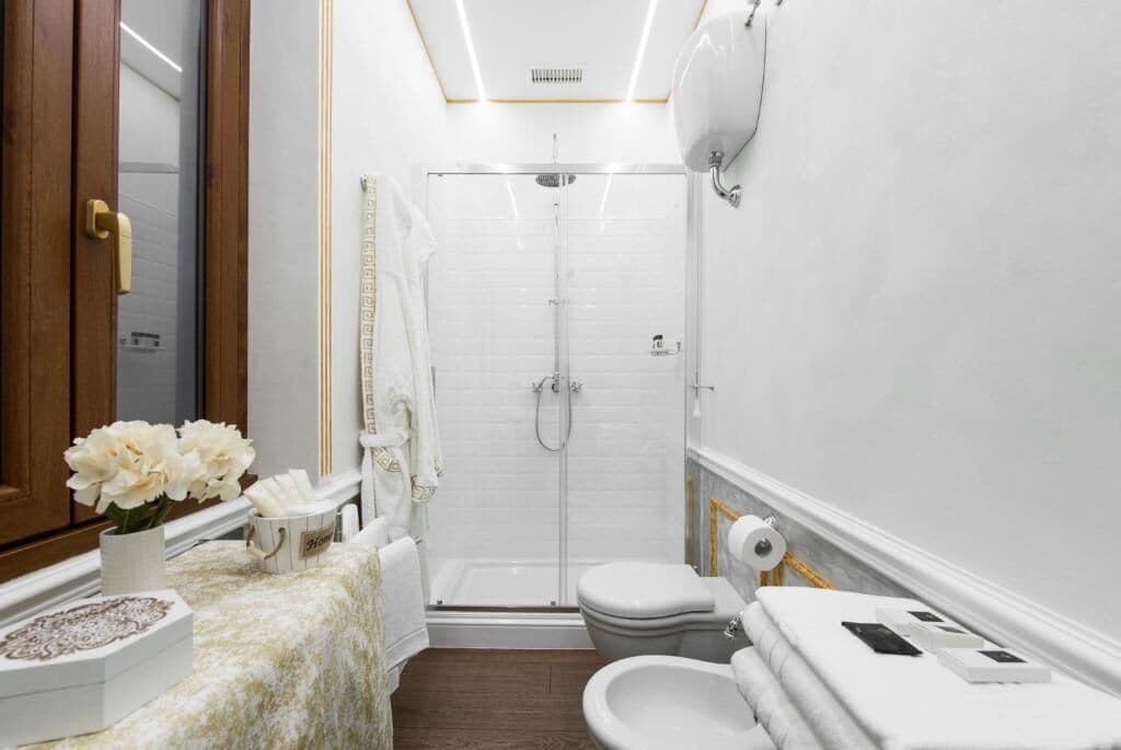 Un baño moderno con ducha, inodoro, bidé y tocador con espejo y perchero.