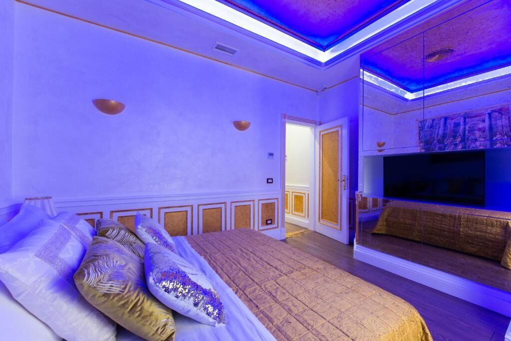 Une chambre à coucher avec un grand lit, une télévision et une porte donnant sur une autre pièce.