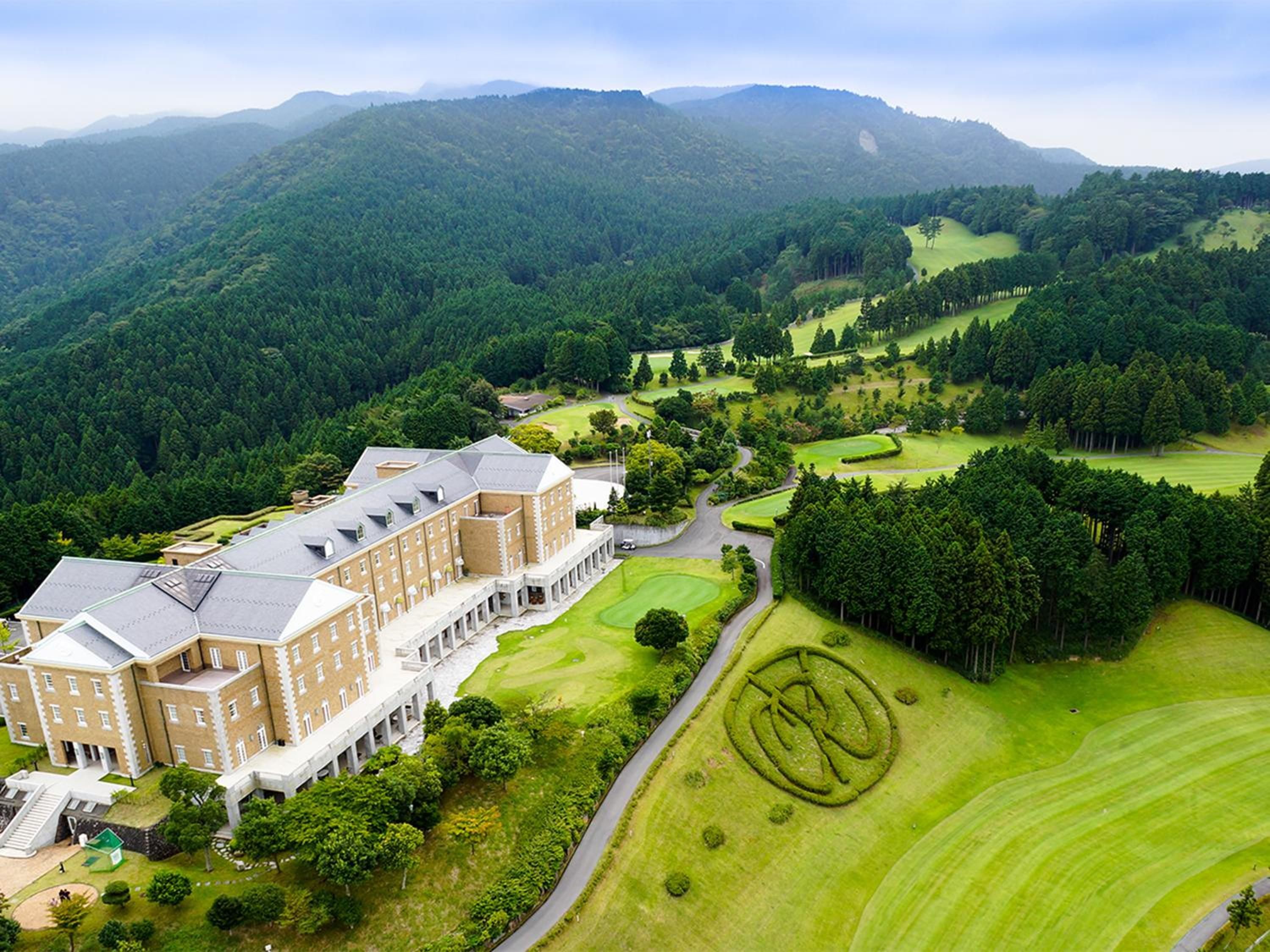 A large building with a symmetrical facade, surrounded by well-maintained lawns and a golf course.