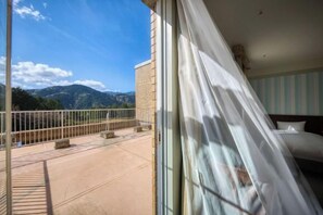 A hotel room with a balcony, a bed, and a view of mountains.