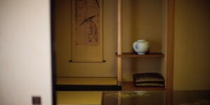 A traditional Japanese interior with a tatami mat floor, a shoji screen, and a white ceramic vase on a shelf.