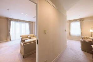 A hotel room with a large bed, a sitting area with a chair, and a window with curtains.