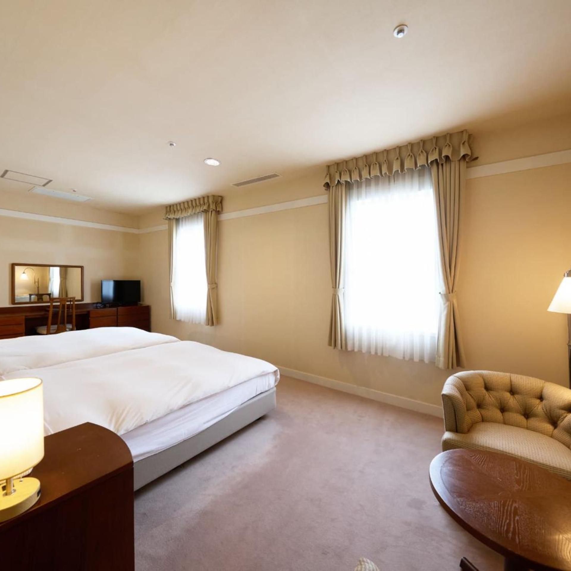 Una habitación de hotel con una cama grande, un escritorio, una silla y un televisor.
