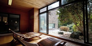 A room with wooden flooring, a stone wall, and a large window overlooking a garden.