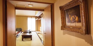 Un pasillo con un banco de madera, una puerta que da a otra habitación y un cuadro enmarcado en la pared.