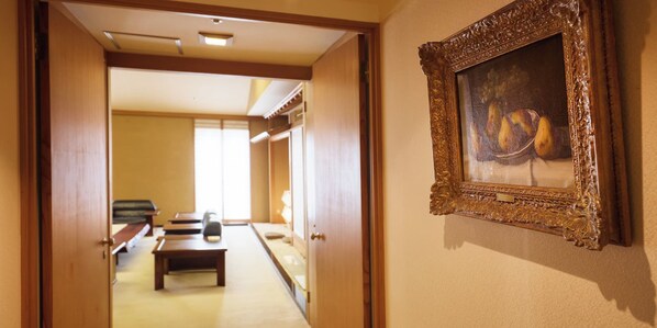A hallway with a wooden bench, a door leading to another room, and a framed painting on the wall.
