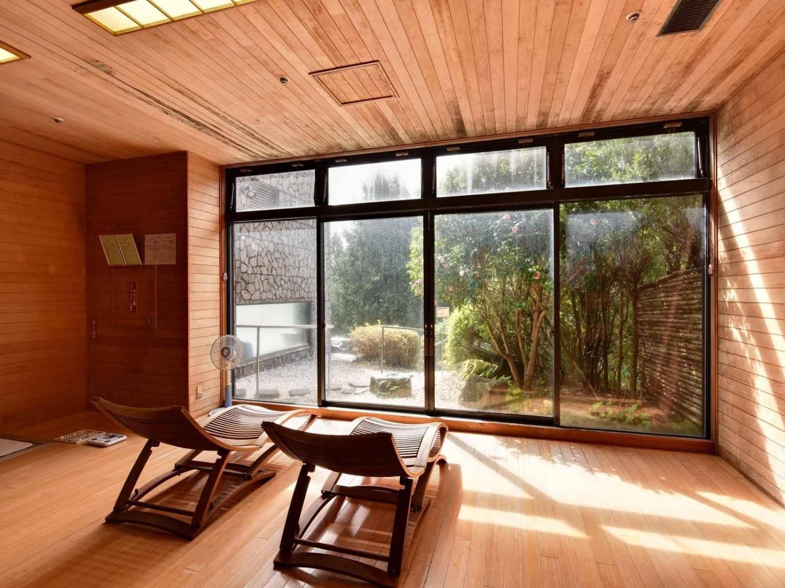Una habitación con piso de madera, un ventanal con vistas a zonas verdes y dos mecedoras.