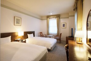 A hotel room with two beds, a desk, a chair, a small table, and a mirror. - Yugashima Golf Club & Hotel Resort (Izu)