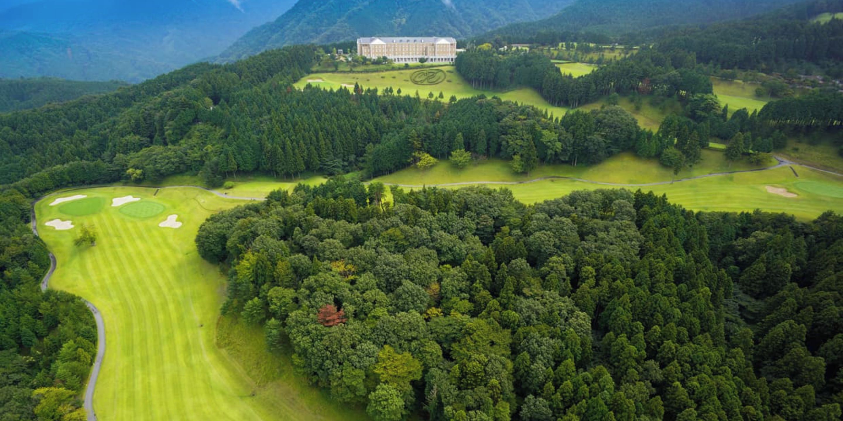 An aerial view of a golf course with a large building in the background.