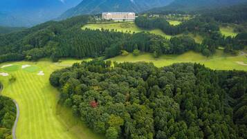 An aerial view of a golf course with a large building in the background.