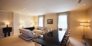 A hotel room with a large dining table, a sofa, and two lamps.