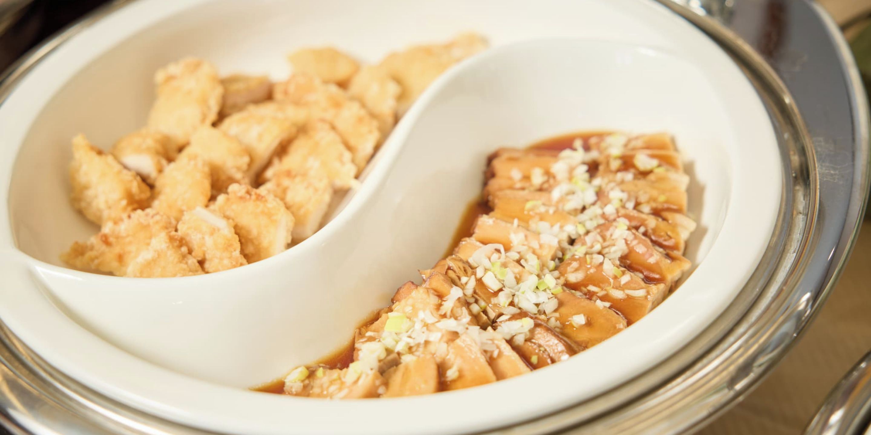 Un plato de cerámica blanca con dos secciones; una contiene alimentos fritos y la otra tiene un elemento glaseado y en rodajas, coronado con nueces picadas.