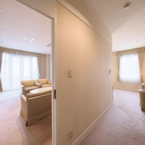A spacious hotel room with a large bed, a sitting area with a sofa, and a view of the city through the window. - Yugashima Golf Club & Hotel Resort (Izu)