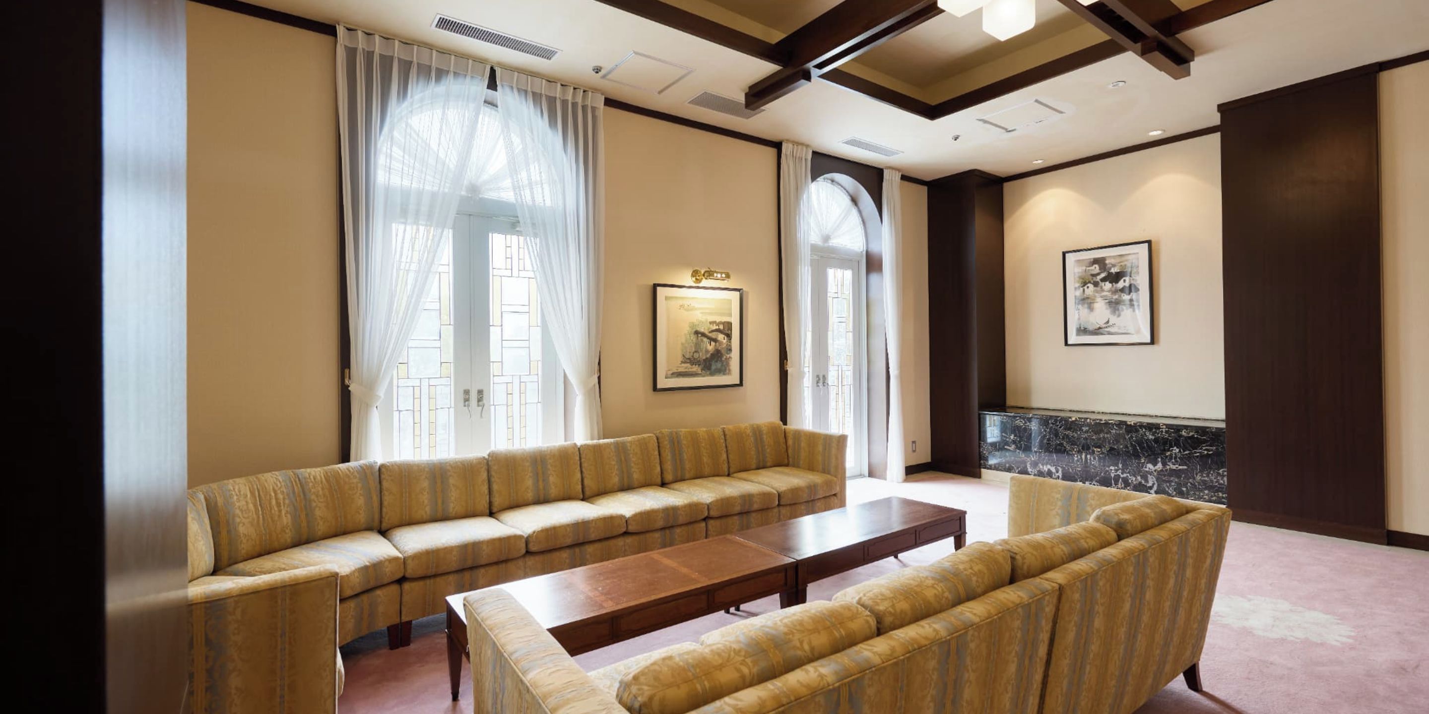 A hotel room with a sofa set, a coffee table, and a painting on the wall.