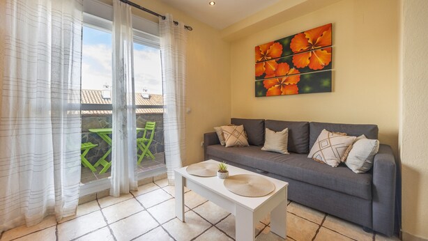 A living room with a sofa, a table with a plant, and a painting of flowers on the wall. - Charming House in Vejer de la Frontera, Cádiz (Vejer de la Frontera)