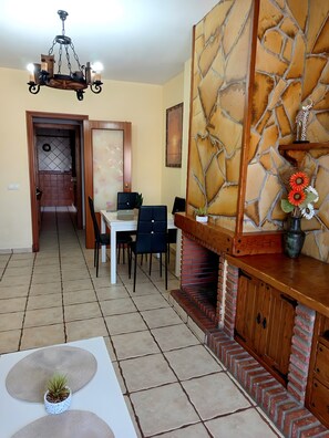 Zona pranzo con camino in mattoni, un lampadario e una parete in pietra.