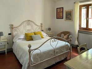 Ein Schlafzimmer mit Bett, Nachttischen, einem Sessel und einem Fenster.