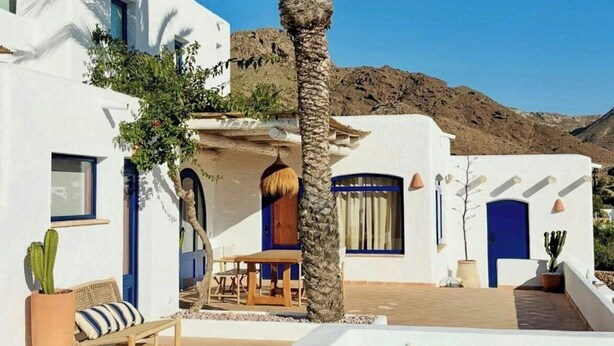 A poolside area with a clear blue pool, white buildings, and a palm tree. - Mediterranean-style house in Cabo de Gata (Almeria)