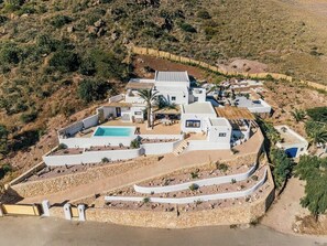 Eine weiße Villa mit Swimmingpool, mehreren Zimmern und einem angelegten Garten.