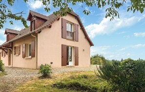 Ein zweistöckiges Haus mit geneigtem Dach, Holzhörnern und einem kleinen Balkon.