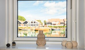 Ein Fenster mit Blick auf ein Ufergebiet, eine Vase und einige Steine im Fensterbrett.