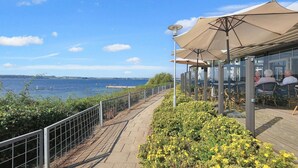 Un restaurante frente al mar con terraza, vista al océano y un paseo a lo largo del agua.