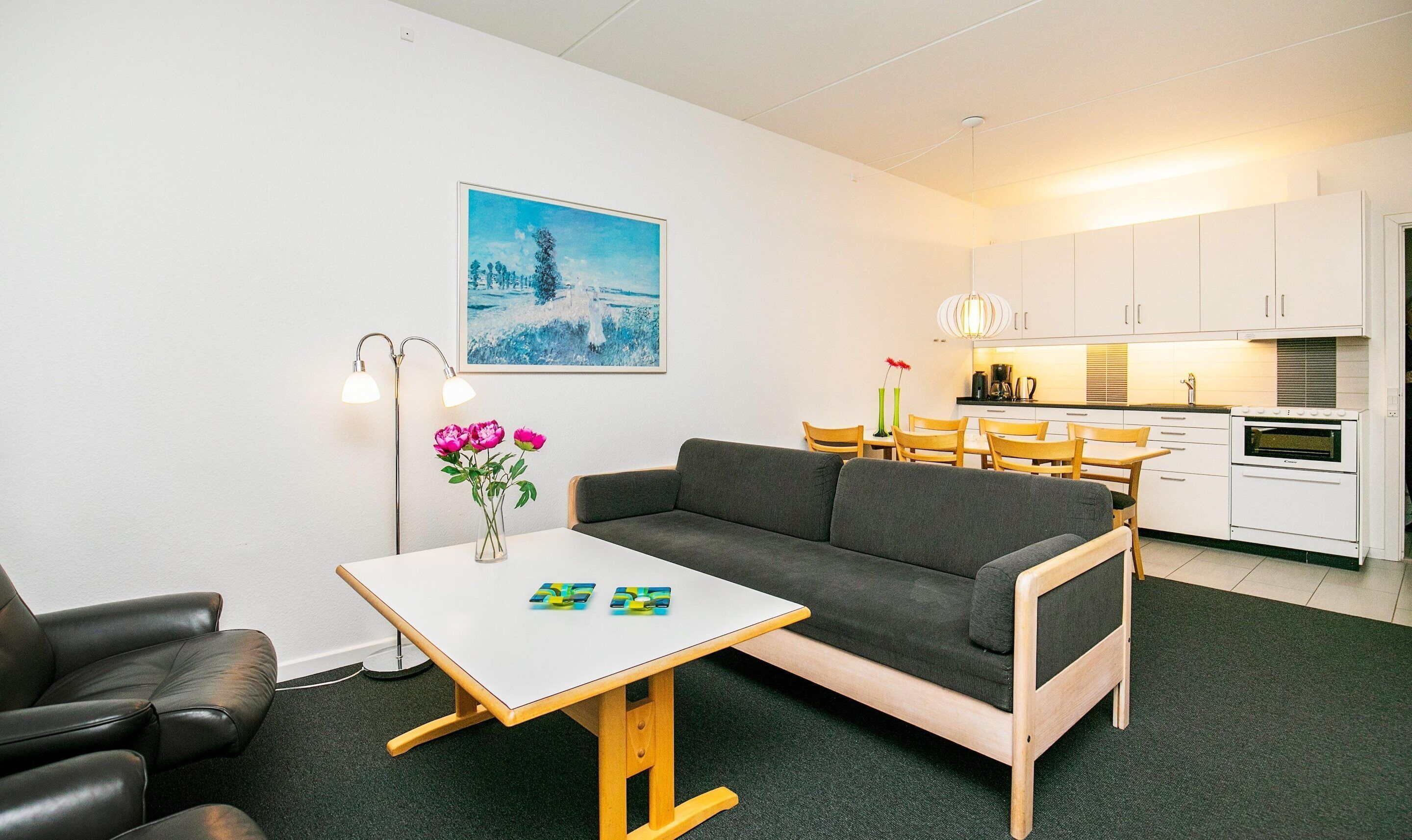 A modern living room with a sofa, a small table, a floor lamp, and a painting on the wall.