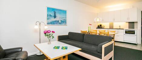 A modern living room with a sofa, a small table, a floor lamp, and a painting on the wall.