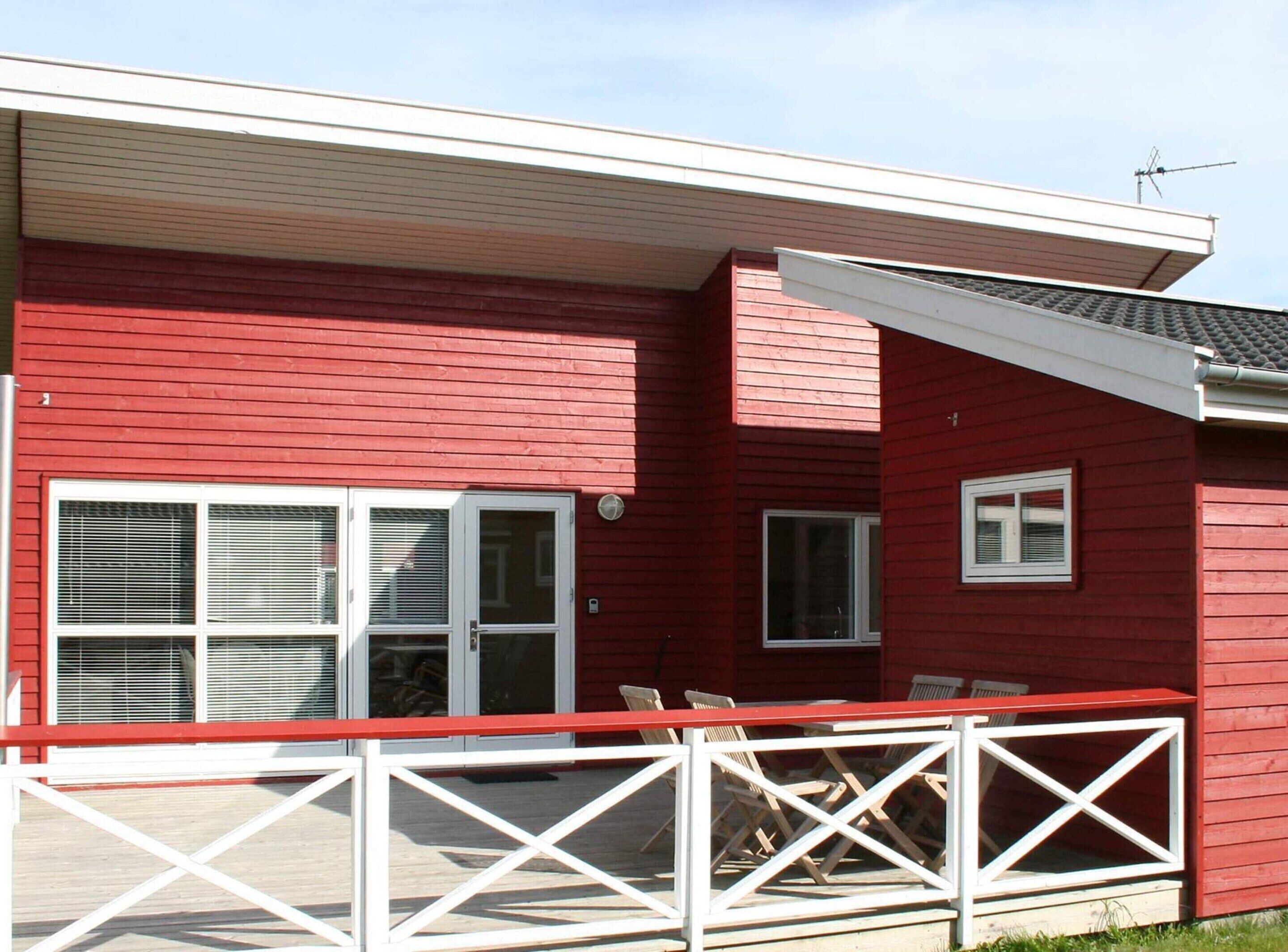 A red building with a covered patio area, a sliding glass door, and a small window.