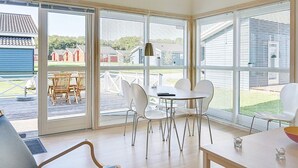 Un interior moderno con comedor, ventanas amplias y vistas al exterior.