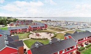En småbåtshamn med båtar, en lekplats och röda byggnader med flera våningar.