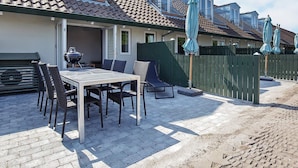 A patio with a table and chairs, a grill, and umbrellas. - Karrebaeksminde Apartments (Karrebæksminde)