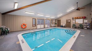 En indendørs swimmingpool med tydelige baneafmærkninger, en loftsvift og en redningskrans på væggen.