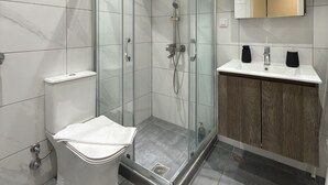 A modern bathroom with a glass-enclosed shower, a toilet, and a vanity with a mirror. - SmartLiving Central Apt 7 (Thessaloniki)