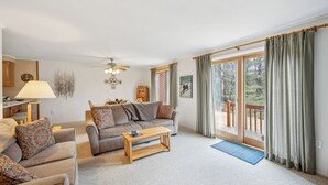 Un salon comprenant un canapé, une table basse, une lampe et une vue sur l’extérieur, accessible par une porte-fenêtre coulissante.