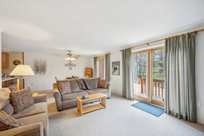 A living room with a sofa, coffee table, lamp, and a view through a sliding glass door.