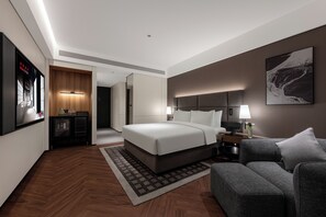 A modern hotel room with a large bed, a sofa, a desk with a lamp, and a wall-mounted TV. - Intercity Hotel Qingdao Sino-Euro Sea (Qingdao)