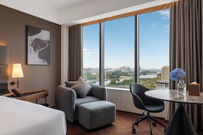 A hotel room with a large window, a sofa, a desk, and a chair. - Intercity Hotel Qingdao Sino-Euro Sea (Qingdao)