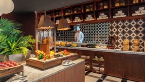 Uma cozinha com um chef, um balcão de buffet e prateleiras com potes.