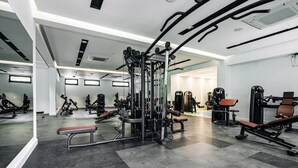 Un gimnasio con diversas máquinas de ejercicio, bancos y espejos.