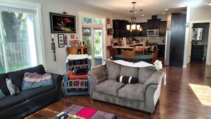 Una sala de estar con sofá, una silla, una mesita y una cocina al fondo.
