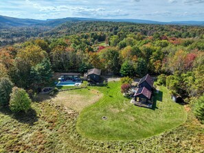 Una casa grande con piscina, rodeada de un paisaje boscoso.