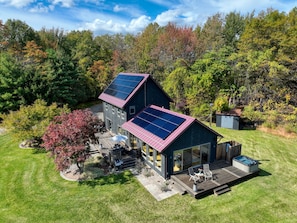 Una casa moderna con paneles solares, una bañera de hidromasaje y una terraza.