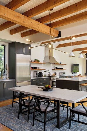 Una cocina moderna con una isla grande, electrodomésticos integrados e iluminación colgante.
