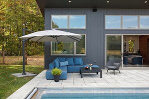 Un espace de vie extérieur moderne avec une piscine, un canapé bleu, une table basse et un fauteuil.