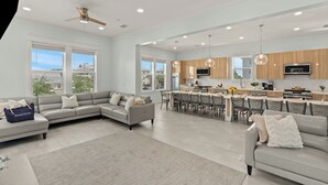 Un espacio habitable amplio con un sofá grande, una mesa de comedor y una cocina con armarios de madera y un televisor.