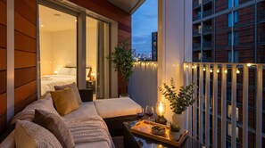 Un balcon avec un canapé, une table à manger et un pot de fleurs.