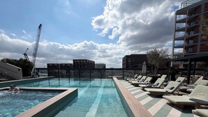 Piscina no terraço com cadeiras de descanso e vista para a cidade.